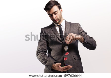Handsome businessman in suit, throwing poker chips from one hand to the other / risky business investment concept/ risk taker 