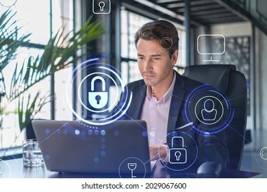 Handsome businessman in suit at workplace working with laptop to defend customer cyber security. Concept of clients information protection and brainstorm. Padlock hologram over office background. - Powered by Shutterstock