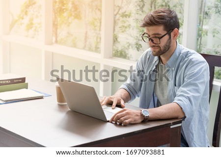 ํYoung handsome businessman using laptop at his office desk