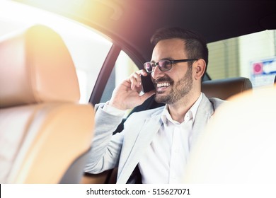 Handsome businessman using mobile phone in car. Happy face.
