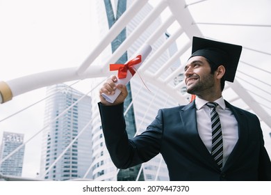Handsome businessman wear graduation degree hat and stand on stair near cityscape, business education concept - Shutterstock ID 2079447370
