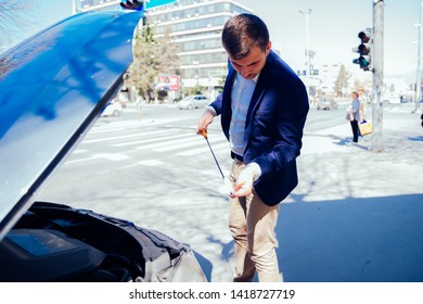 A Handsome Businessman Wearing Blue Blazer Lifting Up The Hood Of His Car And Checking The Oil Level On A Sunny Day Parked On A Busy City Boulevard, White Collar Worker