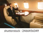 Handsome businessman wearing elegant suit  flying on exclusive private jet - Successful entrepreneur sitting in exclusive business class on airplane, concepts about business and trasportation