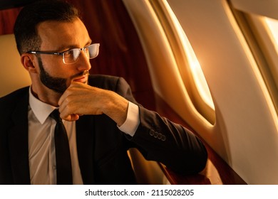 Handsome businessman wearing elegant suit  flying on exclusive private jet - Successful entrepreneur sitting in exclusive business class on airplane, concepts about business and trasportation