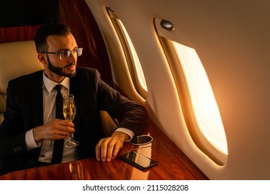 Handsome businessman wearing elegant suit  flying on exclusive private jet - Successful entrepreneur sitting in exclusive business class on airplane, concepts about business and trasportation