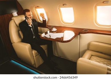 Handsome businessman wearing elegant suit  flying on exclusive private jet - Successful entrepreneur sitting in exclusive business class on airplane, concepts about business and trasportation - Powered by Shutterstock