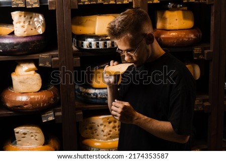 Handsome buyer in cheese shop sniff and enjoy limited gouda cheese. Snack tasty piece of cheese for appetizer