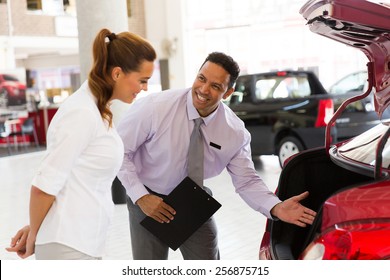 Handsome Car Salesman Showing New Vehicle To Customer