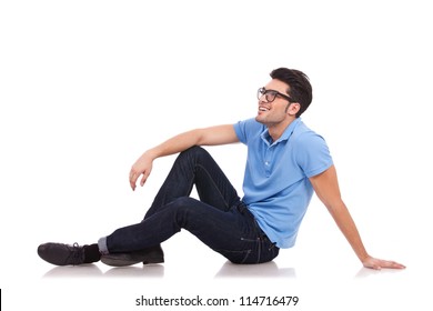 Handsome casual young man laying on the floor and looking away from the camera while smiling. isolated on white