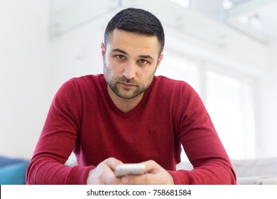 Handsome casual young man using a mobile phone at  home