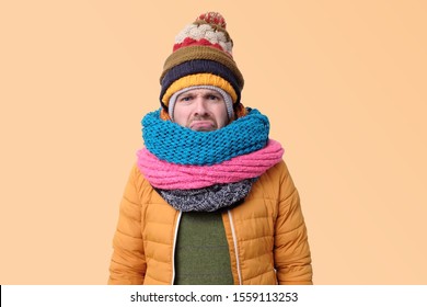 Handsome Caucasian Funny Man In Several Hats And Scarfs Looking Up Being Confused On Yellow Background. Winter Fashion.