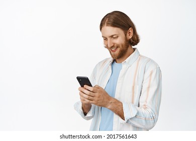 Handsome caucasian guy using mobile phone, looking at screen, white background