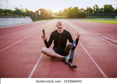 Handsome caucasian handicapped young sporty man dressed in sportswear and with artificial leg sitting on racetrack, listening music over smart phone and singing. - Powered by Shutterstock