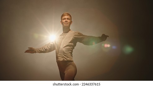 Handsome caucasian male ballet dancer performing pirouette and spinning on stage, wearing white tights, spotted by searchlight and isolated on black background  - Powered by Shutterstock