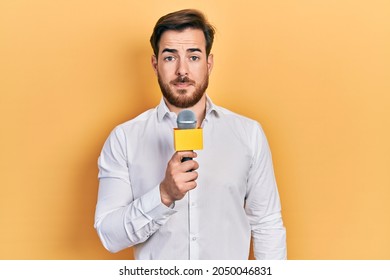 Handsome Caucasian Man With Beard Holding Reporter Microphone Thinking Attitude And Sober Expression Looking Self Confident 