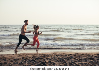 Handsome Caucasian man and beautiful woman running on sandy beach. - Shutterstock ID 1318915148
