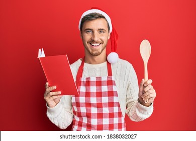 Handsome Caucasian Man Cooking Wearing Baker Apron And Christmas Hat Smiling And Laughing Hard Out Loud Because Funny Crazy Joke. 