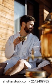 Handsome caucasian man drinking coffee after spa treatments, wearing white robe