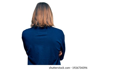 Handsome caucasian man with long hair wearing casual winter sweater standing backwards looking away with crossed arms 