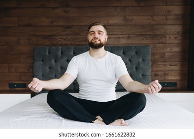 Handsome Caucasian Man Meditating Calmly And Being Mindful On His Bed In Bedroom