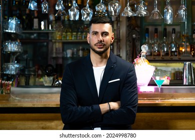 Handsome Caucasian Man Sitting At Bar Counter Holding Whiskey Glass With Ice Cube And Drinking Alcoholic Drink From Barman In Nightclub. Nightlife Holiday Party Celebration And Small Business Concept