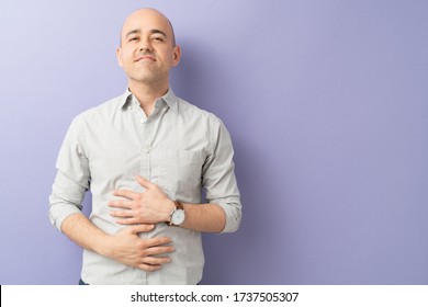 Handsome Caucasian Man Touching His Belly And Looking Satisfied After Eating A Tasty Meal In A Studio