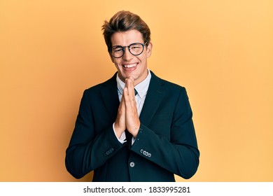 Handsome Caucasian Man Wearing Business Suit And Tie Praying With Hands Together Asking For Forgiveness Smiling Confident. 