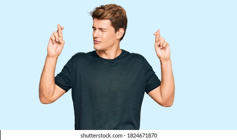 Handsome caucasian man wearing casual clothes gesturing finger crossed smiling with hope and eyes closed. luck and superstitious concept.  - Powered by Shutterstock