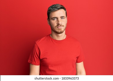 Handsome caucasian man wearing casual red tshirt looking sleepy and tired, exhausted for fatigue and hangover, lazy eyes in the morning. 