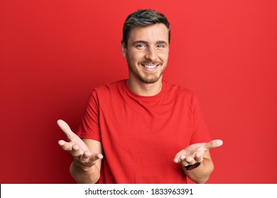 Handsome Caucasian Man Wearing Casual Red Tshirt Smiling Cheerful With Open Arms As Friendly Welcome, Positive And Confident Greetings 