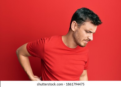 Handsome Caucasian Man Wearing Casual Red Tshirt Suffering Of Backache, Touching Back With Hand, Muscular Pain 