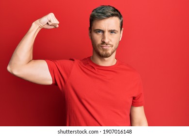 Handsome Caucasian Man Wearing Casual Red Tshirt Strong Person Showing Arm Muscle, Confident And Proud Of Power 