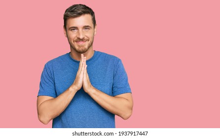 Handsome caucasian man wearing casual clothes praying with hands together asking for forgiveness smiling confident. 