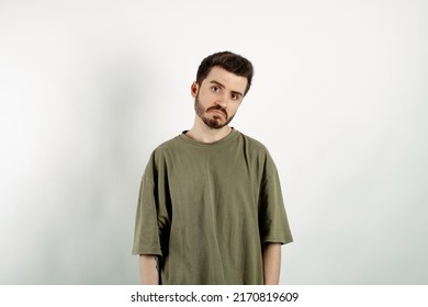 Handsome caucasian man wearing khaki t-shirt posing isolated over white background crying wipes tears losing his job. I don't know.