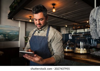 Handsome Caucasian Waiter Scrolling On Digital Ipad Logging Into Account While Standing In Cafe 