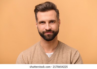 Handsome charismatic bearded man looking at the camera, close-up portrait, studio shot isolated on beige