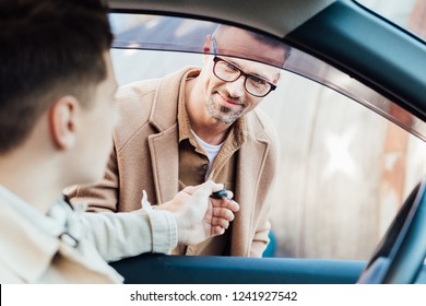 Handsome Cheerful Father Giving Car Key To Teen Son On Street