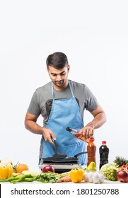 Handsome Cheerful Smiling Indian Man Preparing Meal In The Kitchen,  Healthy Food, Cooking Concept.