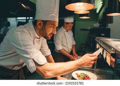 Handsome Chef cook in uniform checking the order at the restaurant kitchen - Powered by Shutterstock