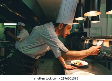 Handsome Chef cook in uniform checking the order at the restaurant kitchen