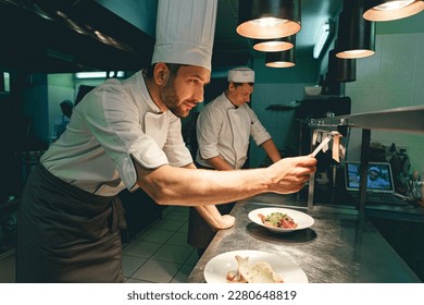 Handsome Chef cook in uniform checking the order at the restaurant kitchen - Powered by Shutterstock