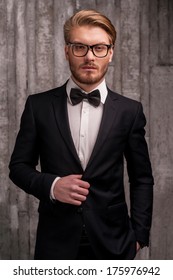 Handsome And Classy. Handsome Young Man In Formalwear And Bow Tie Adjusting His Suit And Looking At Camera