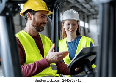 Handsome colleagues in helmets and communicate with each other, man driving forklift, using digital tablet, mobile app working in warehouse. Concept of transportation, cooperation, communication - Powered by Shutterstock