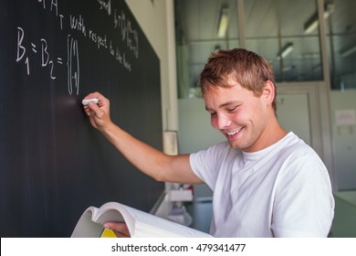 Handsome College Student Solving A Math Problem During Math Class In Front Of The Blackboard/chalkboard (color Toned Image)