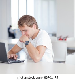 Handsome College Student Using His Laptop Computer In The Campus Common Area/high School Study Room, Absorbed (shallow DOF; Color Toned Image)