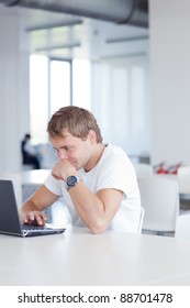 Handsome College Student Using His Laptop Computer In The Campus Common Area/high School Study Room, Absorbed (shallow DOF; Color Toned Image)