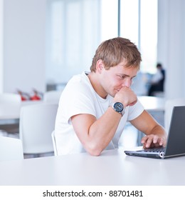 Handsome College Student Using His Laptop Computer In The Campus Common Area/high School Study Room, Absorbed (shallow DOF; Color Toned Image)