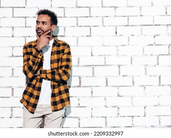 Handsome Confident Hipster Model. Sexy Unshaven Man Dressed In Yellow  Summer Shirt And Jeans Clothes. Fashion Male Posing Near White Brick Wall In Studio At Sunny Day. Isolated