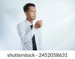 Handsome cool man with Cigarette, going to smoke, isolated on white background, copy space for advertisement. Portrait of asian man in white shirt light cigarette. copy space. Smoking concept