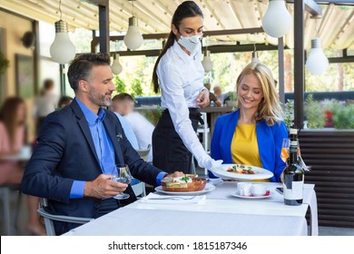 Handsome Couple Having Lunch In The Restaurant, Being Served By Waitress With A Mask, Corona Time